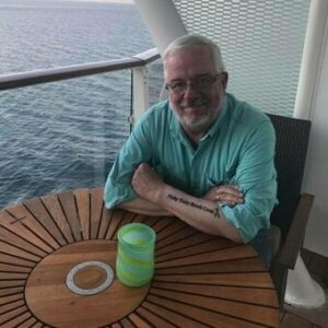 pulmonary fibrosis forum moderator Sam Kirton sitting at a table on the balcony of a ship