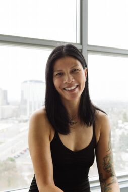 A profile photo shows a woman smiling in a black yoga top, sitting in front of a large window in an industrial-looking area of the city.