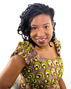 A woman poses for a headshot wearing a green and purple patterned top.