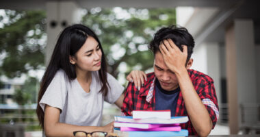 Woman sitting at table consoling tired man with head in his hands