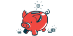 A coin is seen dropping into the top slot of a pig-shaped bank.