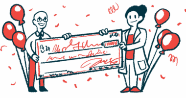 Two people hold a giant check surrounded by balloons and confetti.