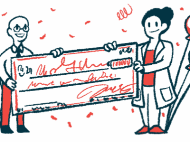 Two people hold a giant check surrounded by balloons and confetti.