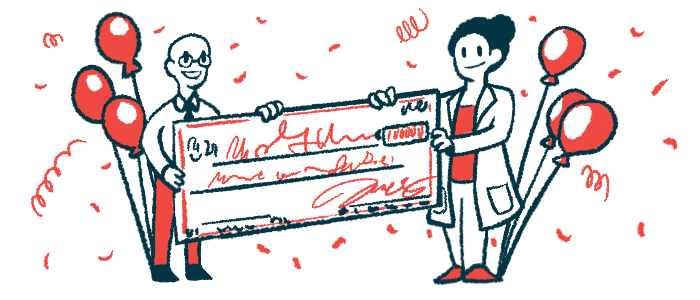 Two people hold a giant check surrounded by balloons and confetti.