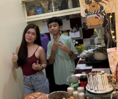 A woman and a boy stand in a kitchen, posing for a photo. 