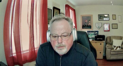 A man wearing headphones is seen working in a home office.