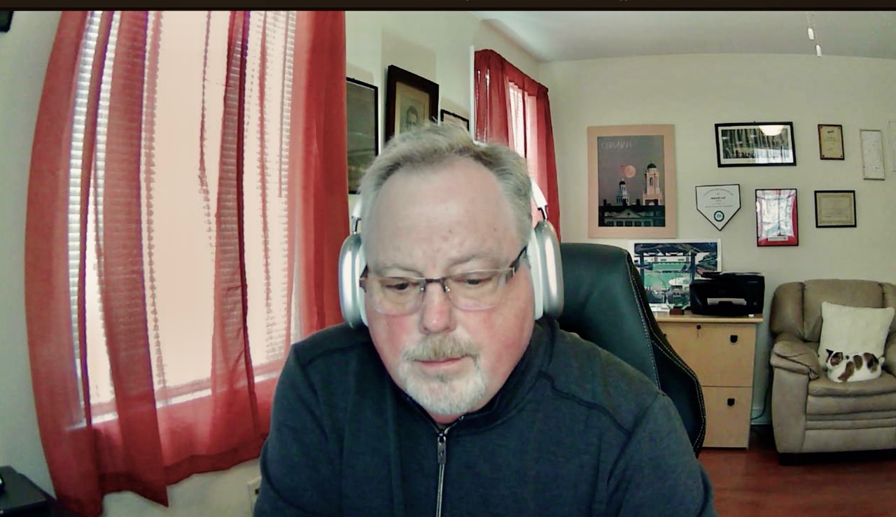 A man wearing headphones is seen working in a home office.